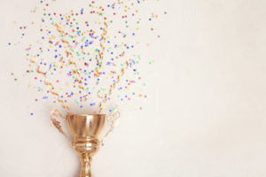Trophy_and_confetti_on_light_background,_top_view_with_space_for_text._Victory_concept