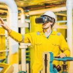 Young_woman_in_a_yellow_work_uniform,_glasses_and_helmet_uses_virtual_reality_glasses_in_industrial_environment,oil_Platform_or_liquefied_gas_plant.