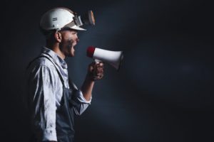 Protesting_miner_man_with_megaphone_on_dark_background