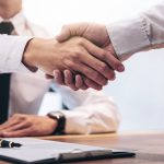 Real_estate_broker_agent_and_customer_shaking_hands_after_signing_contract_documents_for_realty_purchase,_Bank_employees_congratulate,_Concept_mortgage_loan_approval.