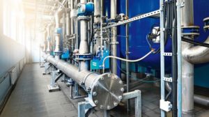 Large_industrial_water_treatment_and_boiler_room._Shiny_steel_metal_pipes_and_blue_pumps_and_valves.