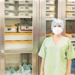 Portrait_of_a_pretty_young_woman_in_scrubs_standing_in_front_of_a_shelf_full_of_clean_and_sterile_medical_instruments_in_a_hospital