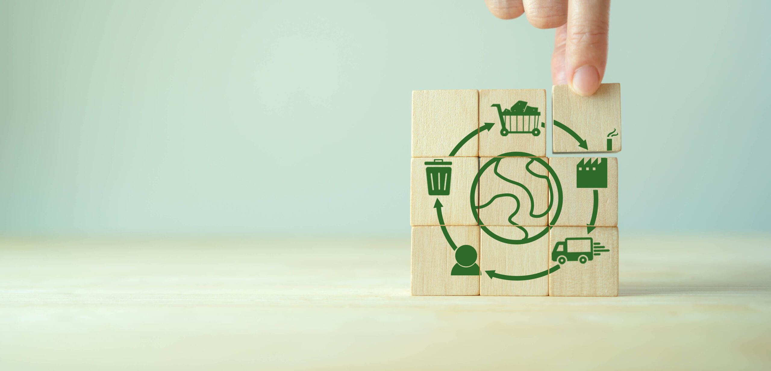 Eine Hand legt einen Holzblock mit Symbolen zum Einkaufszyklus auf.
