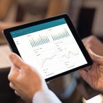 Business_person_analyzing_financial_statistics_displayed_on_the_tablet_screen._Close_up_of_businessman_analyzing_chart_on_digital_tablet._Closeup_of_man_hands_holding_digital_tablet_and_looking_a_stock_market_reports.