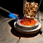 pieces_of_gold_loaded_into_metallurgical_furnace_with_fire_for_melting_